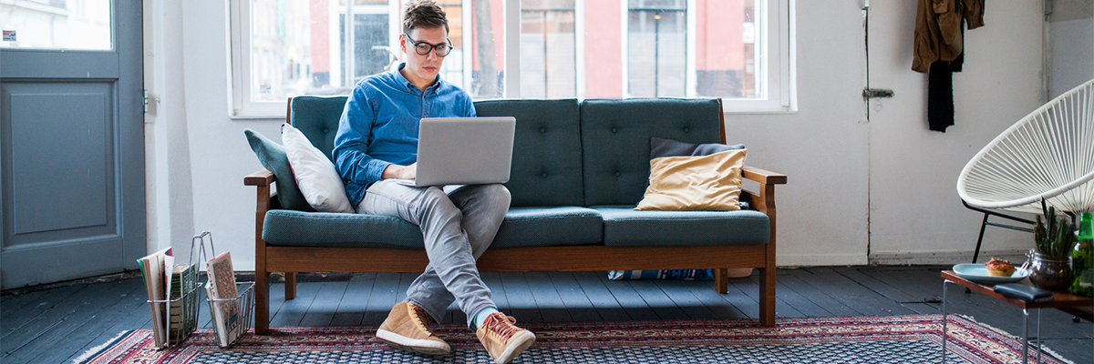 Man Sitting On Sofa Working On Laptop